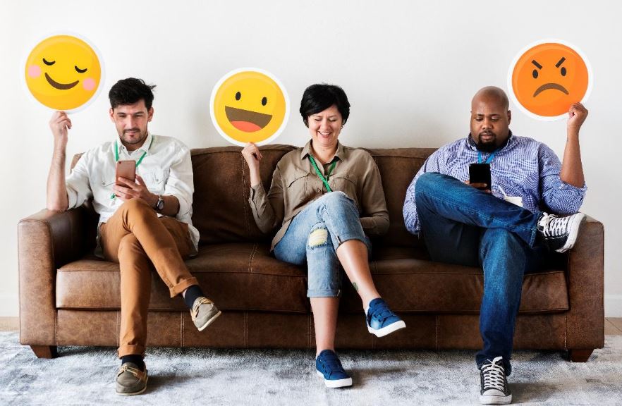 three people on sofa holding emoji signs