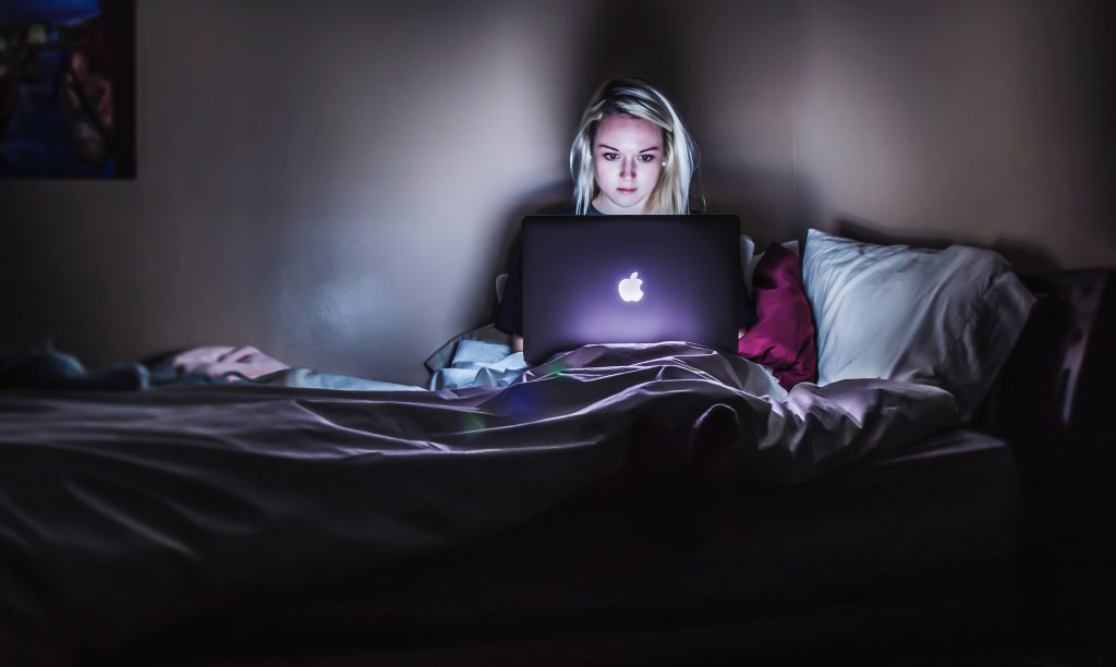 Woman lying in bed with her laptop working at night