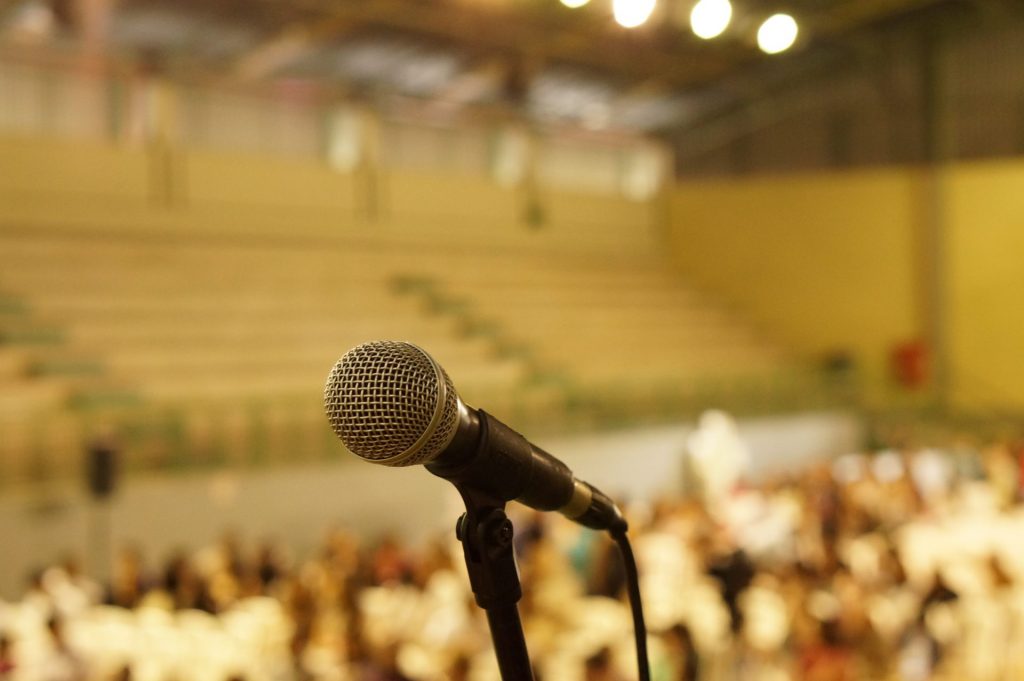 microphone on an empty stage with people in the audience