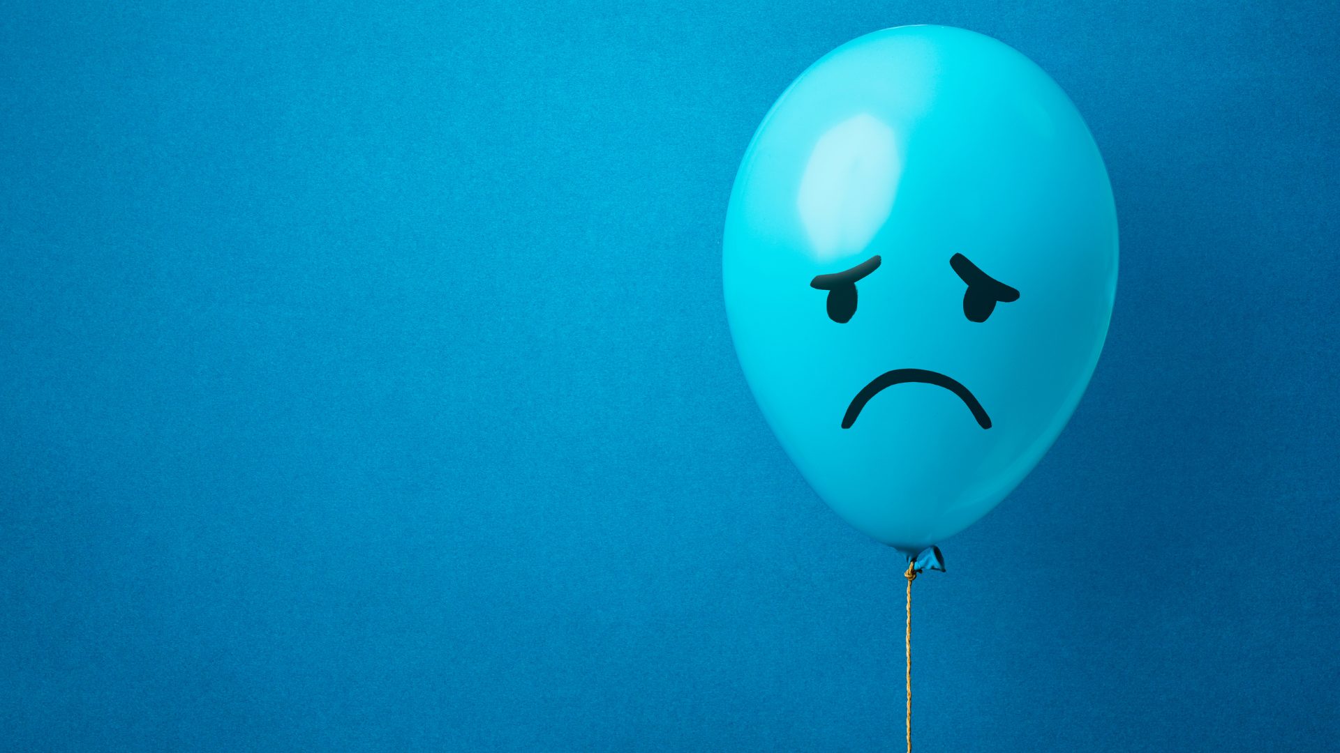 Blue balloon with a sad face on a blue background